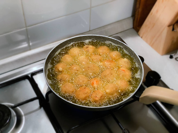 frying round meatballs in a pan with boiling oil. Homemade food. Modern domestic kitchen - Photo, Image