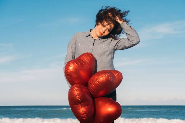 Happy brunet nainen tilalla sydämen muotoinen ilmapalloja rannalla Ystävänpäivä. - Valokuva, kuva