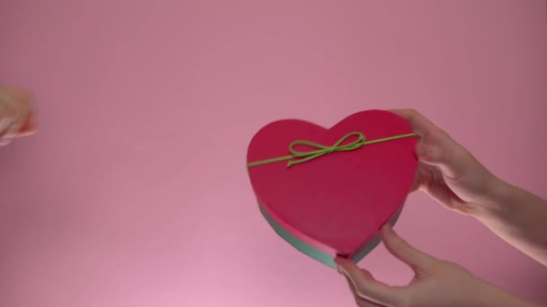 Regalo del día de San Valentín de mano a mano, caja de regalo sobre fondo rosa - Imágenes, Vídeo