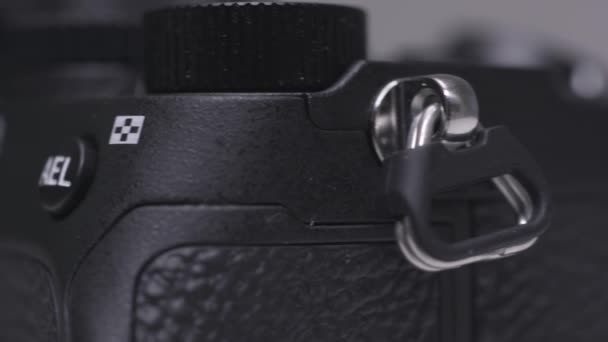 Close-up van een metalen carabine op een professionele foto- of videocamera. Actie. Camerabevestigingsmiddel voor een riem voor veilig vervoer van apparatuur. - Video