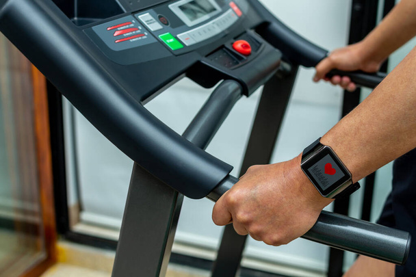 Close-up of a man's hand with a smartwatch with an application heart on a treadmill. Cardio training concept in a gym - Foto, imagen