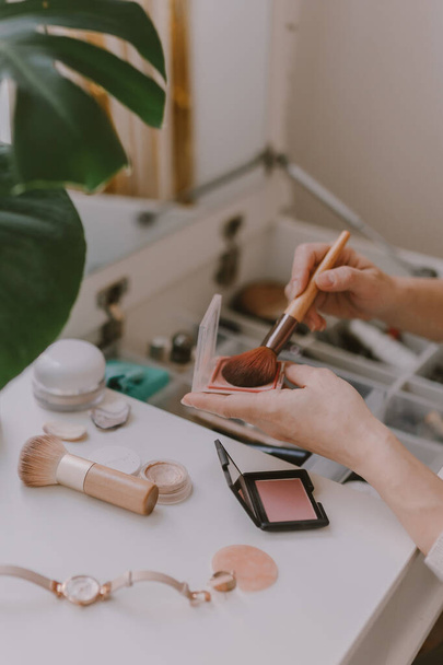 Everyday beauty routine. Make up artist. Dressing vanity. Women's hands. Pastel colors. In front of the mirror. Palettes, brushes, mascara, lipstick. White bright bedroom. Early morning light. - Photo, Image