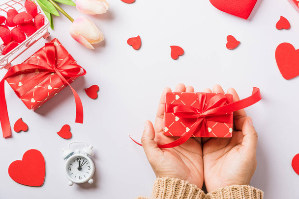 Valentine's day and birthday. Woman hands holding gift or present box decorated and red heart surprise on white background, Female's hand hold gift box package in craft paper Top view flat lay - Photo, Image