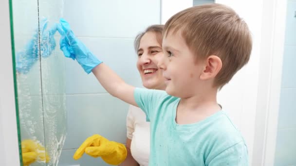 Ev temizliği ve ev işi yaparken küçük oğlu olan mutlu bir anne kirli aynaya resim çiziyor. Aile birlikte iyi vakit geçiriyor.. - Video, Çekim