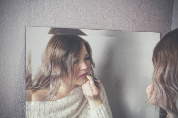 bela jovem mulher colocando maquiagem com batom na frente do espelho - Foto, Imagem