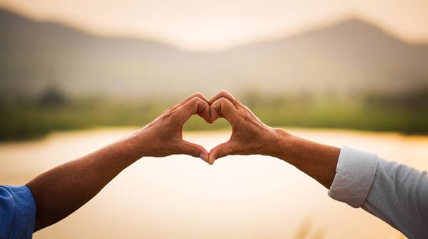 Liebe und Valentinstag Konzept. Ein glückliches älteres Paar zeigt Herzzeichen, Liebessymbol, glückliche Ehe, Seniorengesundheit und Beziehung. - Foto, Bild