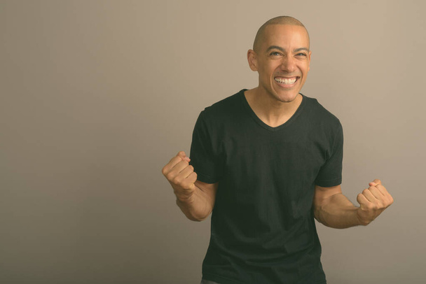 Handsome bald man wearing black shirt against gray background - Photo, Image