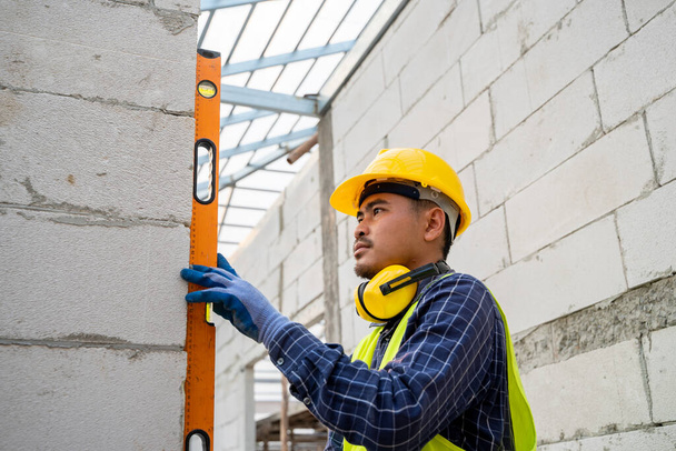 Працівник будівництва вимірює рівень стіни у вікні У будинку, що будується, рівень використовується для установки дверних конструкцій і вікон
. - Фото, зображення
