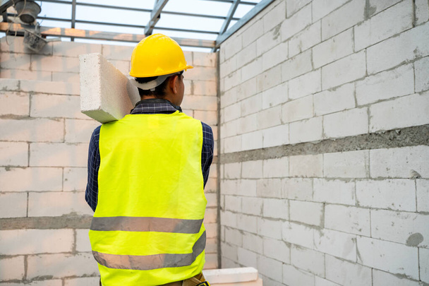 Metselaar maken betonnen muur door cement blok en gips in het nieuwe huis in aanbouw. - Foto, afbeelding