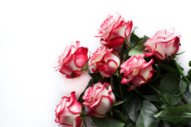 大きな明るいピンクのバラは白い表面にあります。バレンタインデーの花束、クローズアップ、水平方向 - 写真・画像