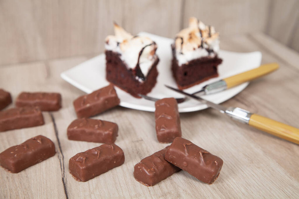Leckere Schokoladenbonbons mit Kuchen auf einem hölzernen Hintergrund.  - Foto, Bild