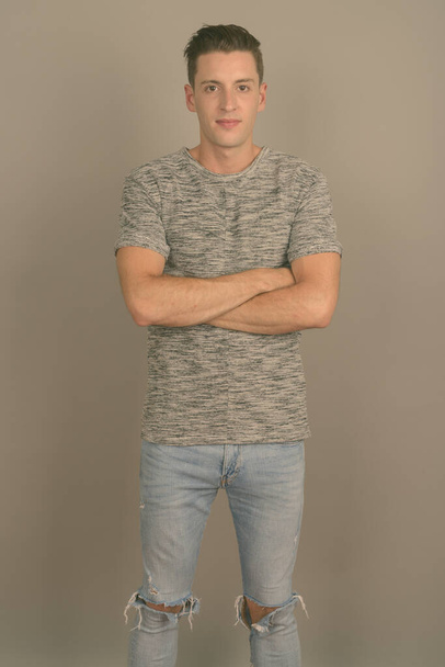 Mladý pohledný muž v šedé košili na šedém pozadí - Fotografie, Obrázek