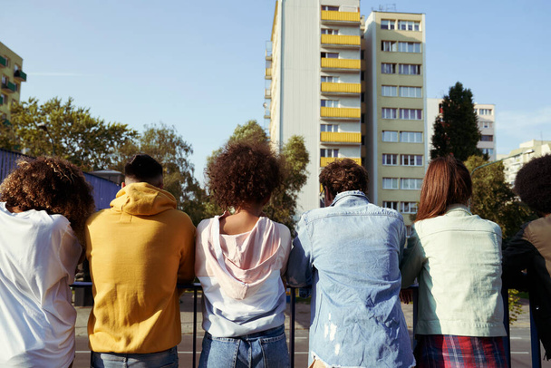 Vista posteriore di amici in piedi contro ringhiera in città                                - Foto, immagini