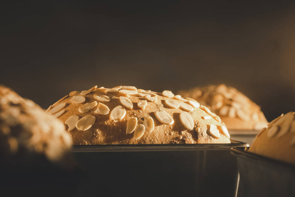 close-up bakken zuurdesem pruimenbrood belegd met gesneden amandel in de oven - Foto, afbeelding