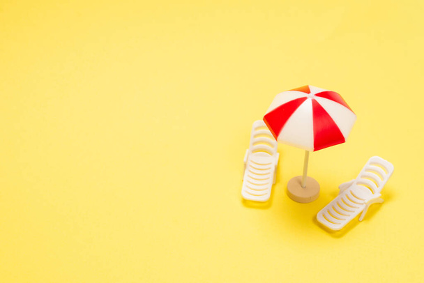 Два шезлонга и красный зонтик на желтом фоне. Копирование пространства. - Фото, изображение