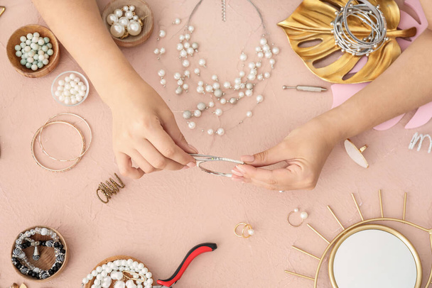 Female designer making jewelry on color background - Photo, Image