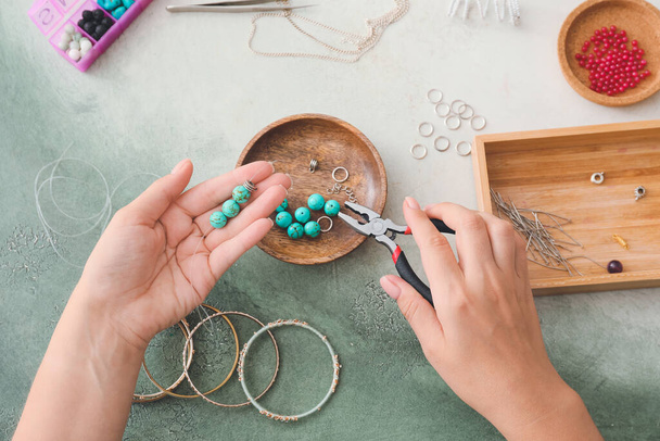 Vrouwelijke ontwerper het maken van sieraden op lichte achtergrond - Foto, afbeelding