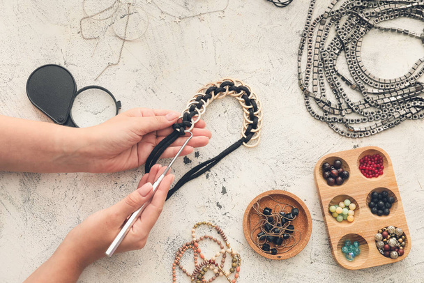 Vrouwelijke ontwerper het maken van sieraden op lichte achtergrond - Foto, afbeelding