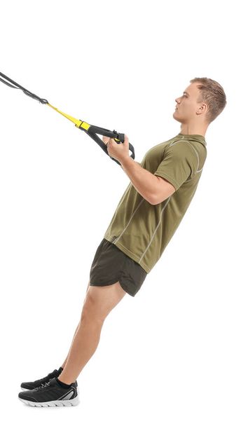 Sporty young man training with TRX straps on white background - Фото, зображення