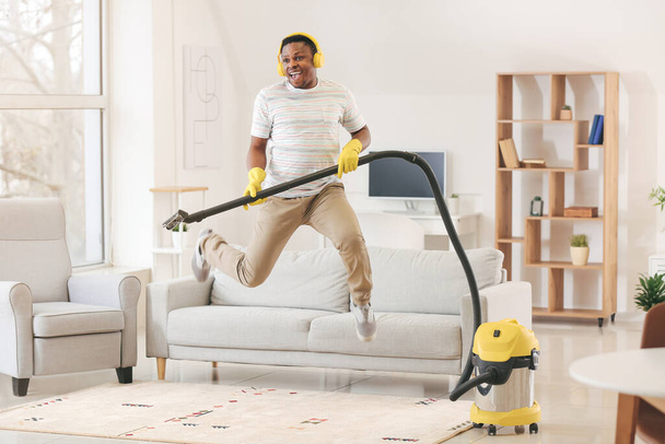 Afroamerikaner amüsiert sich beim Staubsaugen seiner Wohnung - Foto, Bild