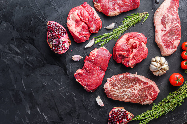 Alternatív nyers marhahús szeletek felső pengével, chuck roll és rump steak, fűszerekkel és gránátalma felülnézetben, hely a szövegnek - Fotó, kép