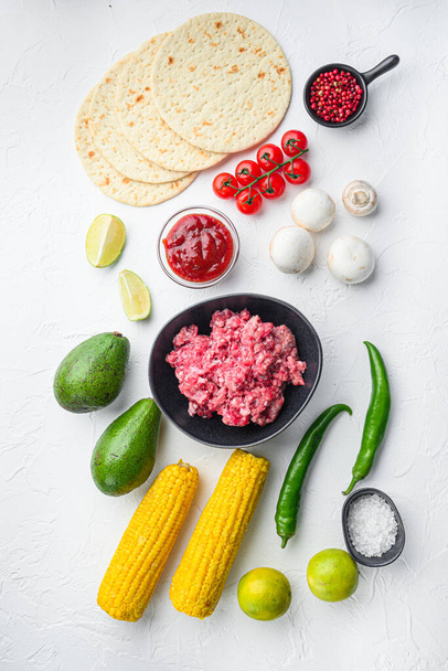 Zutaten für Tacos mit Rinderhackfleisch, Maistortillas, Chili, Avocado, auf weißem Hintergrund. Ansicht von oben - Foto, Bild