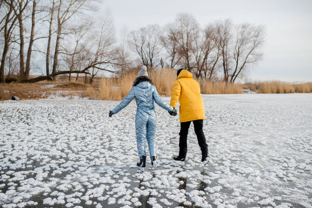 a loving couple holding hands skating on a frozen lake - Foto, afbeelding