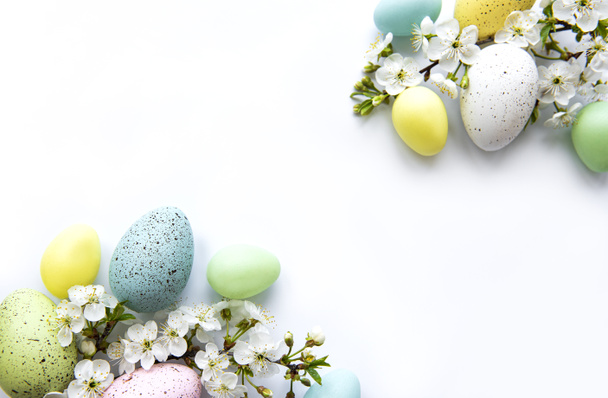 Colorful Easter eggs with spring blossom flowers isolated over white background. Colored Egg Holiday border.  - Фото, изображение