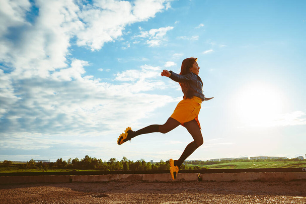 une fille jaune en jupe saute haut avec ses jambes écartées comme une ballerine contre le ciel - Photo, image