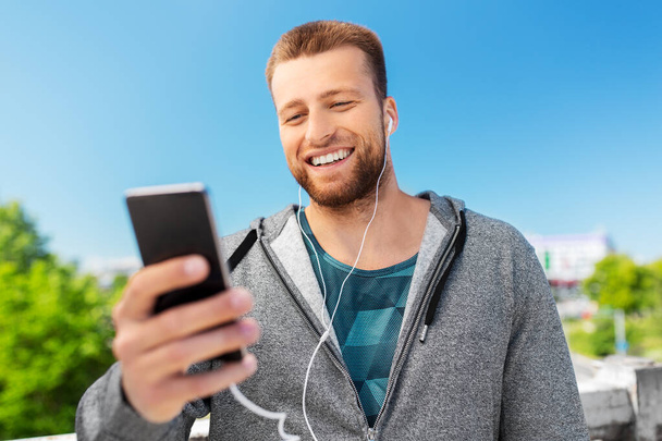 smiling young man with earphones and smartphone - Foto, afbeelding
