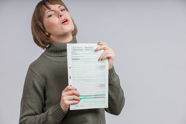 woman with a tax form makes a wry face - Photo, Image