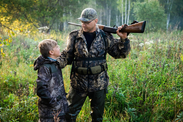 Padre e figlio in piedi insieme all'aperto con fucile da caccia. - Foto, immagini