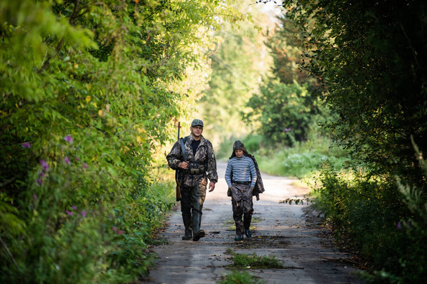 Отец и сын идут вместе на улицу с винтовкой для охоты - Фото, изображение