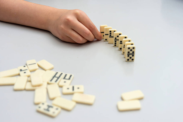 A menina está tentando construir uma pequena parede com dominós. - Foto, Imagem