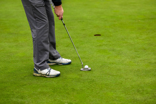 Gros plan d'un joueur de golf qui avec un putt poche la balle sur le vert - Photo, image