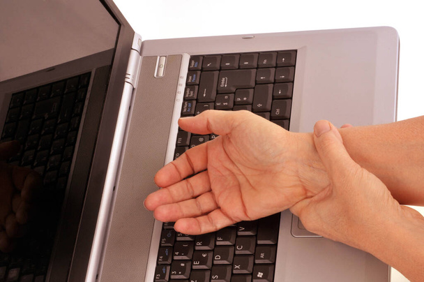 Ktoś cierpiący na nadgarstek i trzymający nadgarstek nad klawiaturą komputera  - Zdjęcie, obraz