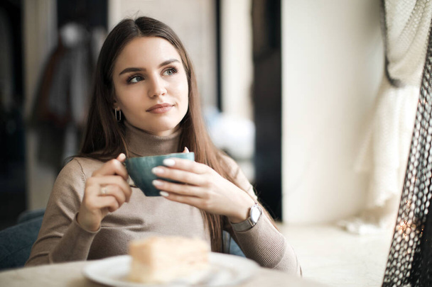 Happy pretty woman in cafe with cup of coffee and cake - Фото, зображення
