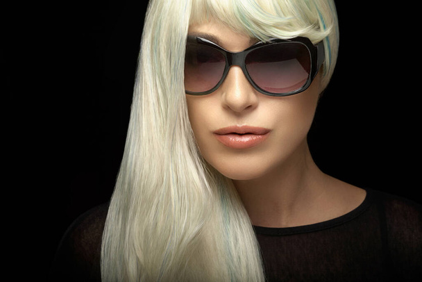Moda portret atrakcyjnej blondynki ze zdrowymi długimi srebrnymi włosami, w czarnych okularach przeciwsłonecznych, patrząc w kamerę. Zbliżenie izolowane na czarnym tle z miejscem na tekst - Zdjęcie, obraz