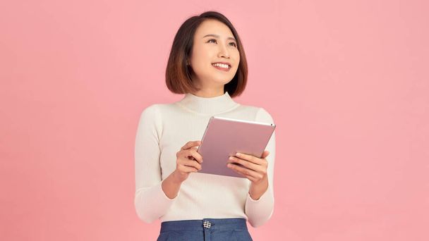 Beauty at work. Confident young women holding digital tablet while standing against pink background - 写真・画像