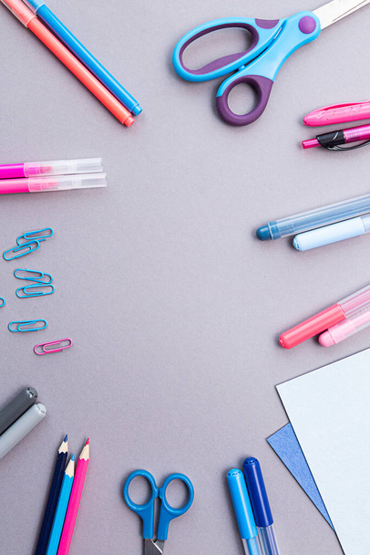 Various stationery in pink and blue colors, blank sheets of paper, on a gray background with copy space. Flat lay with pencils, scissors, pens, paper clips, felt-tip pens and sheets of paper. - Foto, Imagem