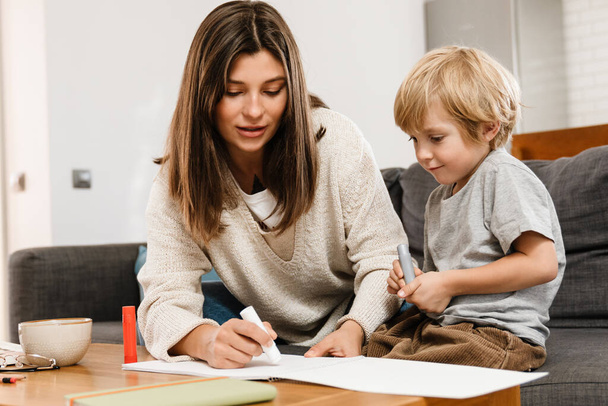 Image of young beautiful woman drawing at home with her son - Фото, изображение