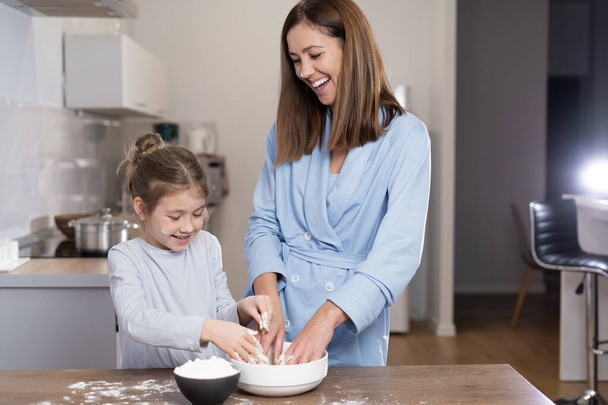 maman et fille ensemble dans la cuisine pétrir la pâte dans un bol. Concept de cuisine ensemble à la maison. Espace de copie. - Photo, image