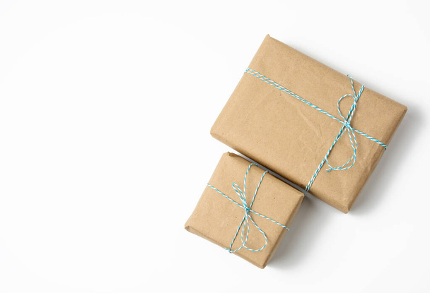 boîte carrée enveloppée dans du papier kraft brun et attachée avec une corde, cadeau sur fond blanc, espace de copie - Photo, image