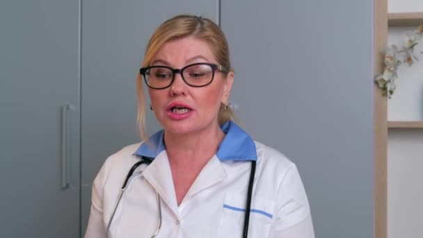 Kaukasische arts heeft een online ontmoeting met de patiënten die met hen praten met behulp van een laptop - Video