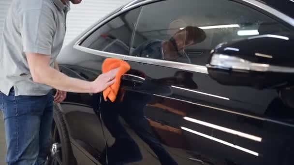 Man polishes the car, uses a microfiber cloth and polish to wipe the cars body. Intensively wiping the car surface. - Πλάνα, βίντεο