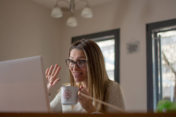 Žena pracující na laptopu v domě. Na volné noze ve vzdálené práci. Studentka se učí on-line přes počítač. Blogger nebo novinář píše nový článek. - Fotografie, Obrázek