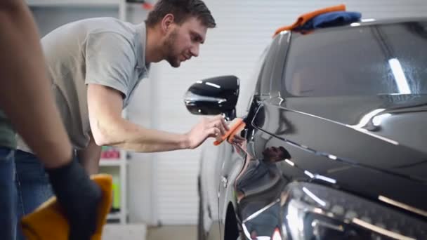 Professional Car Ceramics Worker brengt een laag keramiek beschermende regenkap op een auto. - Video