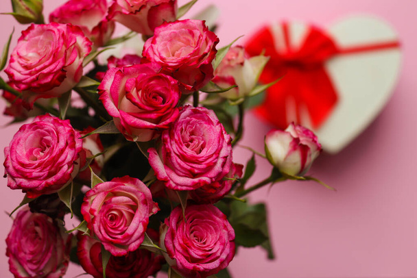Beautiful bouquet of roses on a blurred pink background with a heart-shaped box. Valentines Day and love concept. Greeting card. Selective focus, close-up - Fotografie, Obrázek