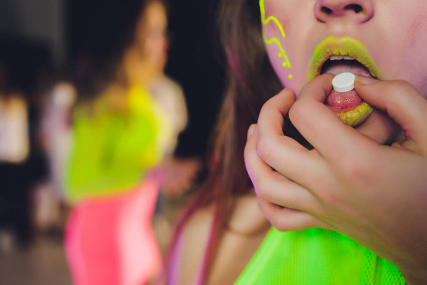 beautiful girl with lsd on tongue in nightclub with pink smoke. - Photo, image