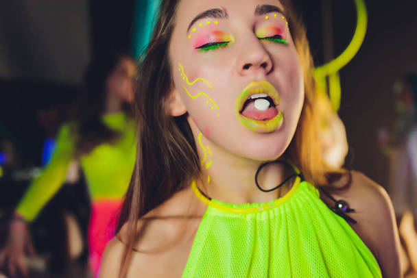 beautiful girl with lsd on tongue in nightclub with pink smoke. - Photo, Image